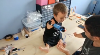 Un mozo catalán faille unha prótese con pezas de Lego a un neno con discapacidade
